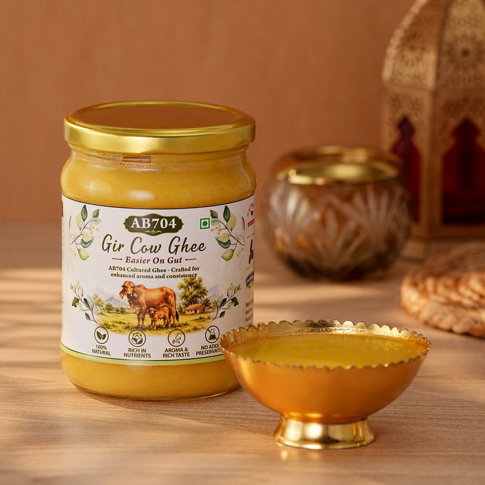 A 500 ml jar of AB704 lit by warm evening light beside a brass ghee bowl